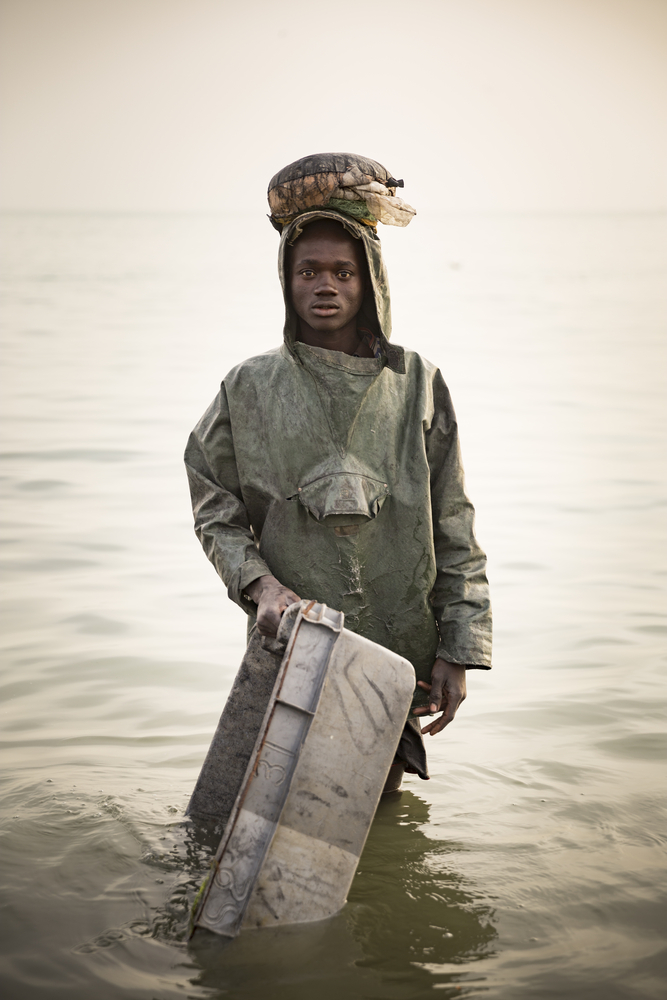 Porteur de caisse poisson attendant les pêcheurs. Port de Joal. Sénégal.